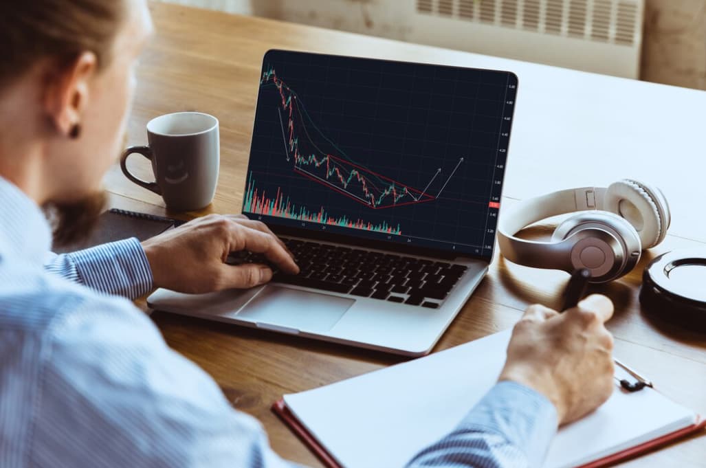 A person analyzing a cryptocurrency trend chart on a laptop